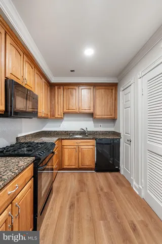 a kitchen with granite countertop a stove top oven a sink dishwasher and cabinets with wooden floor