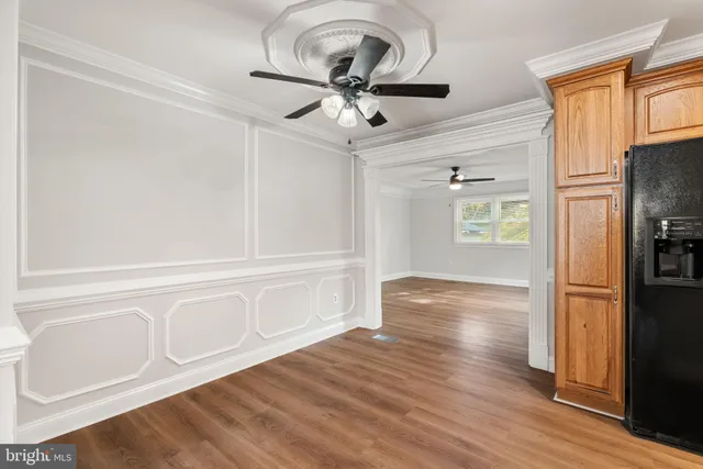 a view of a livingroom with wooden floor a ceiling fan and windows