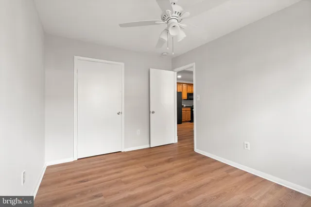 a view of empty room with wooden floor and ceiling fan