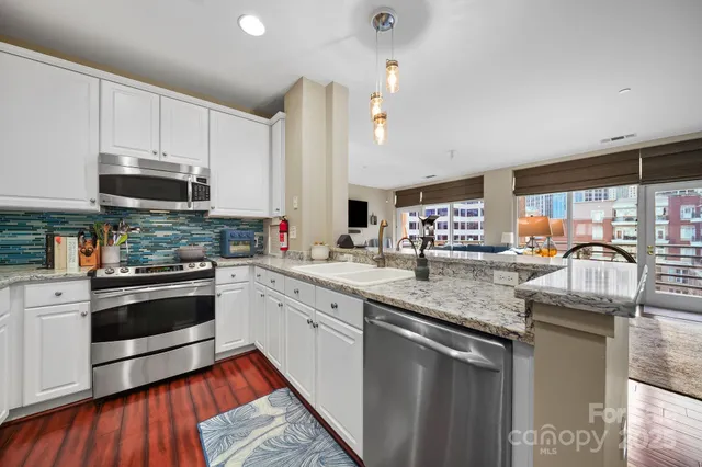 a kitchen with stainless steel appliances granite countertop a stove a sink and a microwave