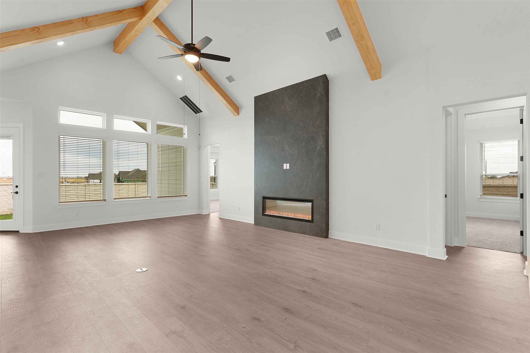 17316 Hope Bergman Road Pflugerville, TX 78660 - Photo 8 of 39 Unfurnished living room with high vaulted ceiling, a fireplace, beam ceiling, wood finished floors, and a ceiling fan