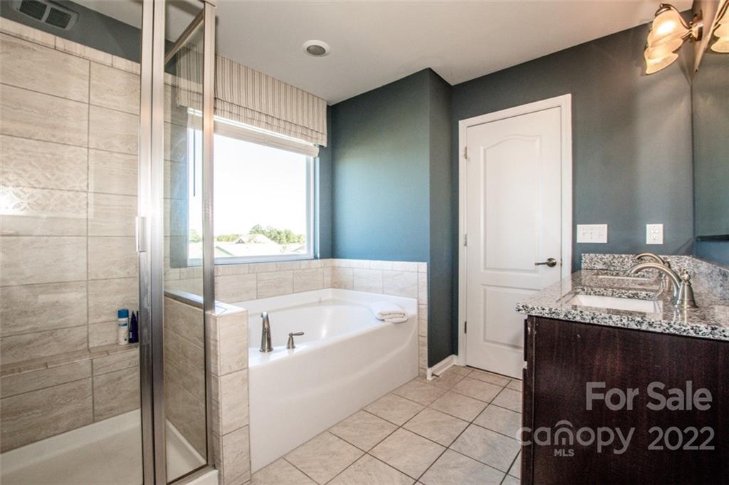 107 East Neel Ranch Road Mooresville, NC 28115 - Photo 26 of 48 a bathroom with a granite countertop sink a mirror and a bathtub