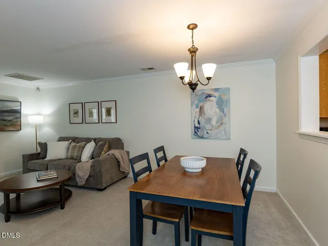 a view of a dining room with furniture a chandelier and a window