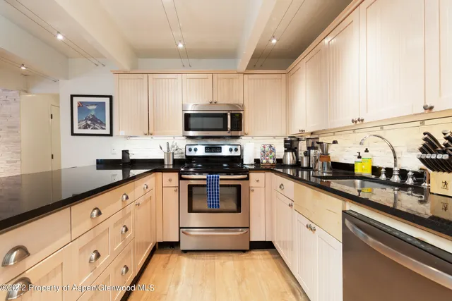 a kitchen with granite countertop a sink stainless steel appliances and cabinets