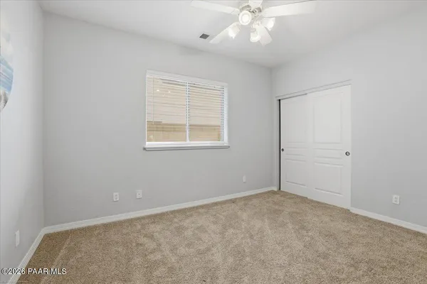 an empty room with a chandelier fan and windows