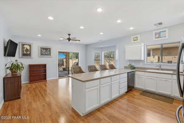 a large white kitchen with wooden floor and stainless steel appliances