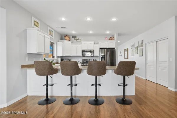 a kitchen with stainless steel appliances granite countertop wooden floor and chairs