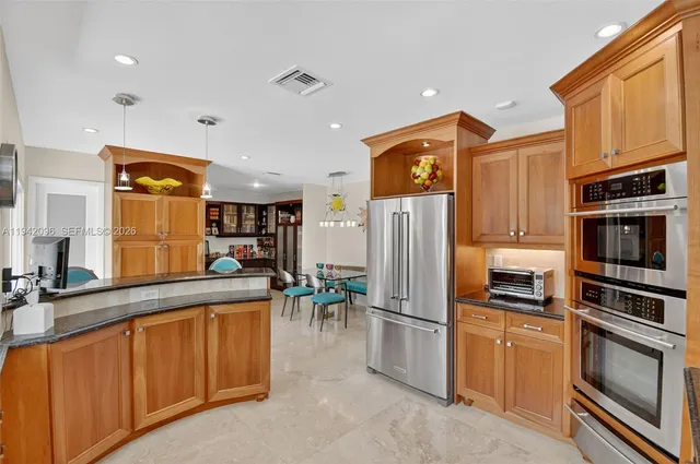 a dining room with stainless steel appliances furniture a rug and a view of kitchen