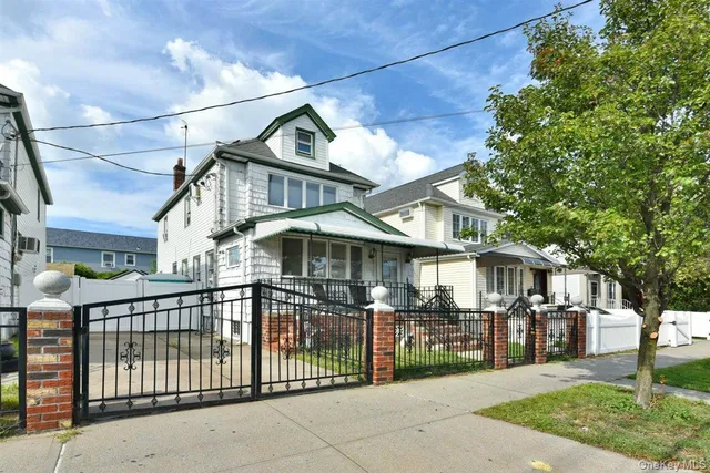 a view of a white house with iron fence