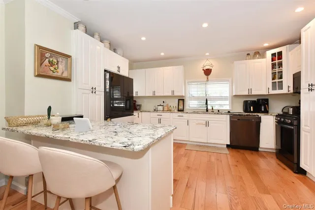 a large kitchen with kitchen island a stove a sink a refrigerator and a dining table with wooden floor