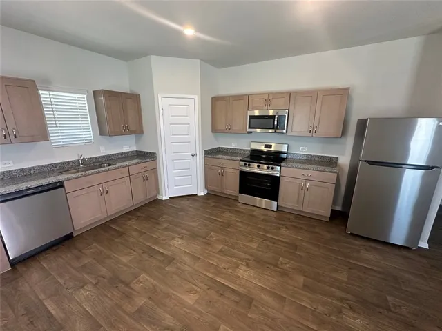 a kitchen with stainless steel appliances granite countertop a refrigerator a stove top oven a sink and dishwasher