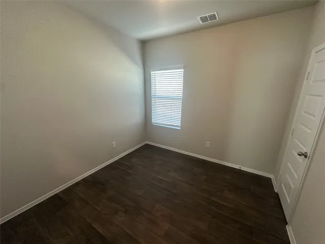 an empty room with wooden floor and window