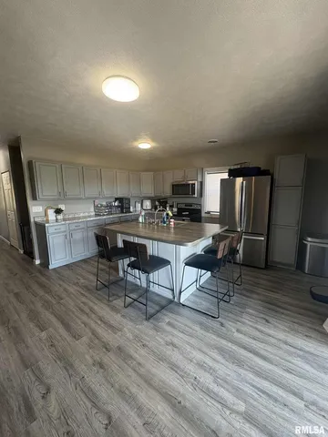 a living room with stainless steel appliances furniture and wooden floor