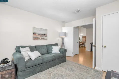 a living room with furniture and a walk in closet with wooden floor