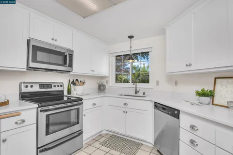 a kitchen with cabinets stainless steel appliances a sink and a window