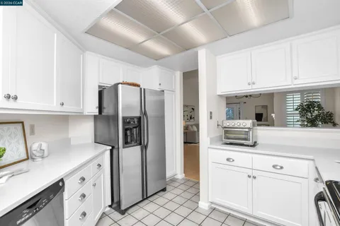 a kitchen with white cabinets and refrigerator