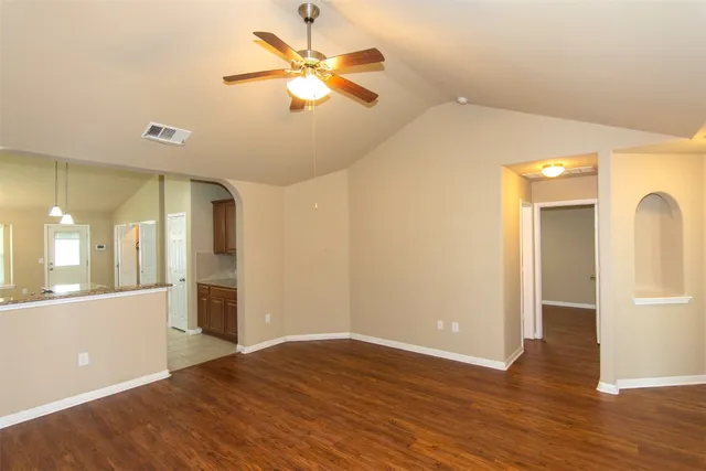an empty room with wooden floor fan and windows