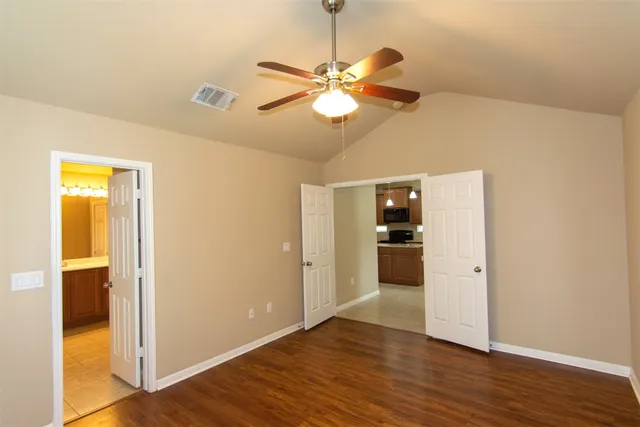 an empty room with wooden floor and windows