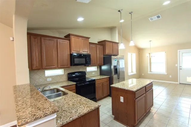 a kitchen with stainless steel appliances granite countertop a sink a stove a refrigerator and a refrigerator