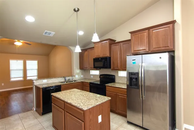 a kitchen with stainless steel appliances granite countertop a refrigerator a sink a stove and oven