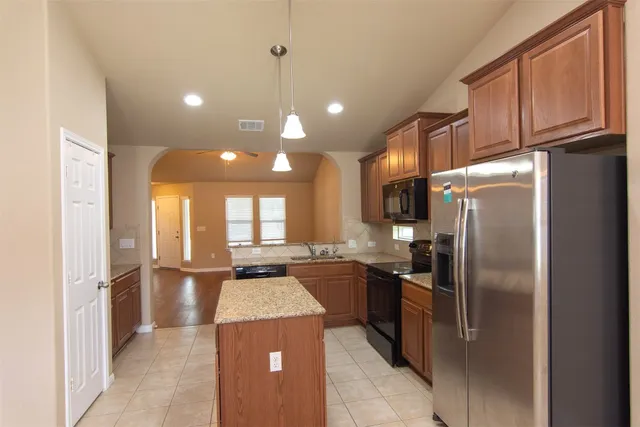 a kitchen with stainless steel appliances granite countertop a refrigerator and a stove top oven