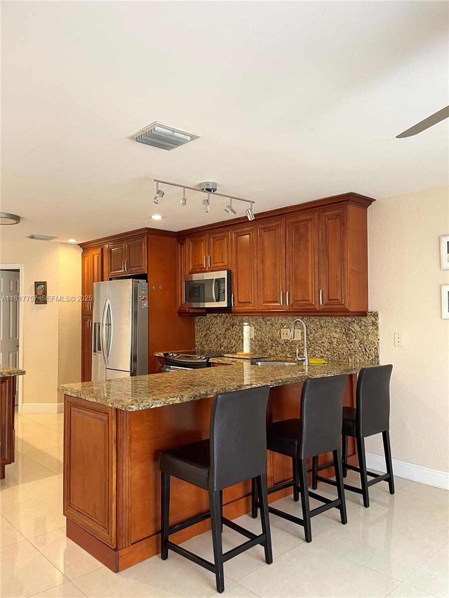 10290 Southwest 139th Court Miami, FL 33186 - Photo 14 of 66 a kitchen with granite countertop a table chairs stove and cabinets