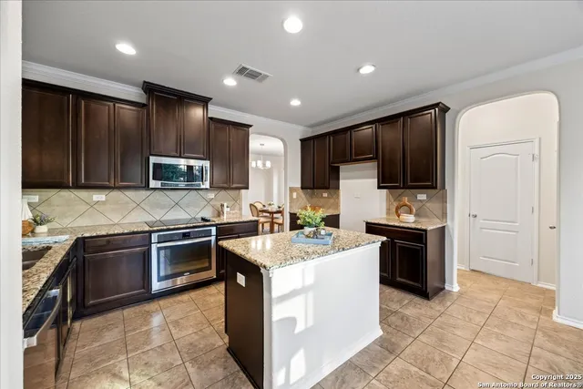 a kitchen with stainless steel appliances granite countertop a stove top oven a sink a counter top space and cabinets