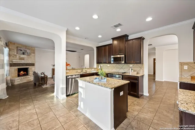 a kitchen with a stove a sink a counter top space and living room view
