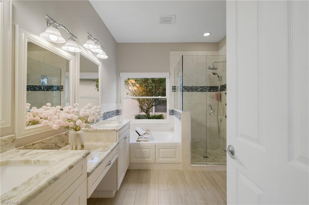 17959 Modena Road Miromar Lakes, FL 33913 - Photo 19 of 48 a bathroom with a granite countertop sink a large mirror and a bathtub