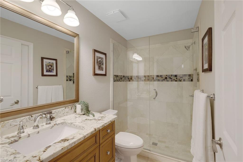 17959 Modena Road Miromar Lakes, FL 33913 - Photo 22 of 48 a bathroom with a granite countertop sink a toilet a mirror and shower