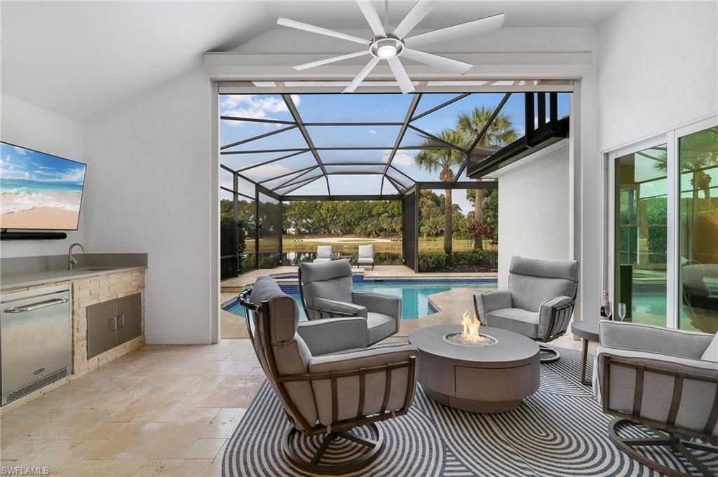 17959 Modena Road Miromar Lakes, FL 33913 - Photo 26 of 48 a living room with furniture a flat screen tv and a floor to ceiling window