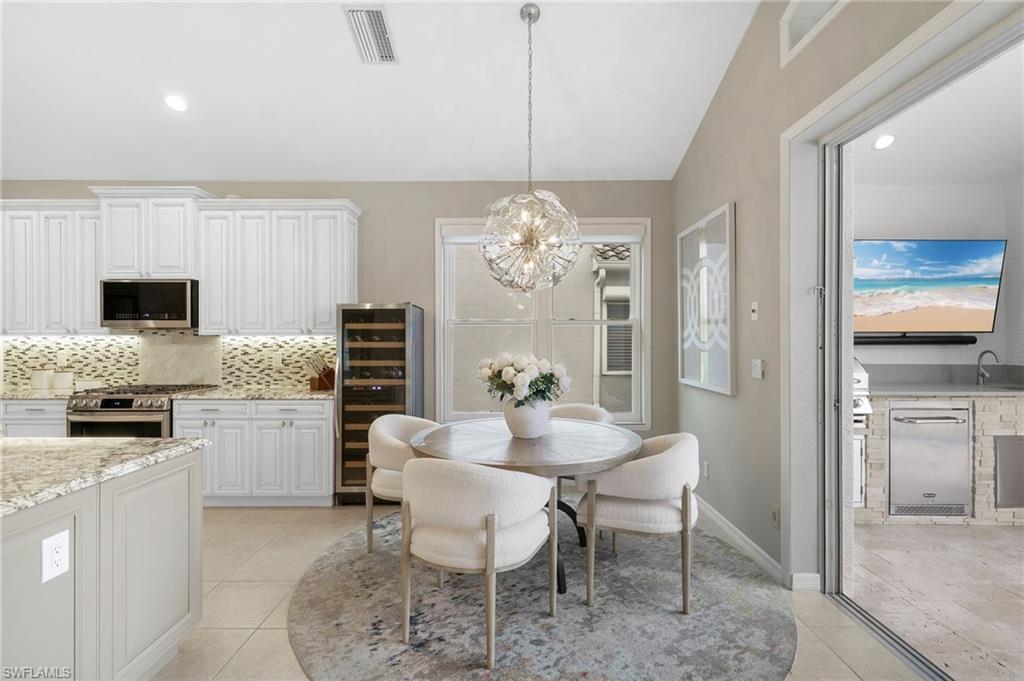 17959 Modena Road Miromar Lakes, FL 33913 - Photo 10 of 48 a kitchen with a dining table chairs stainless steel appliances and cabinets