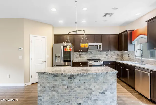 a large kitchen with granite countertop a sink a counter top space appliances and cabinets