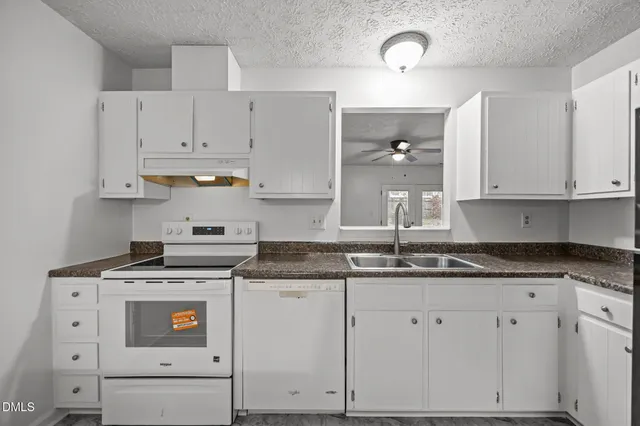a kitchen with granite countertop white cabinets and white appliances