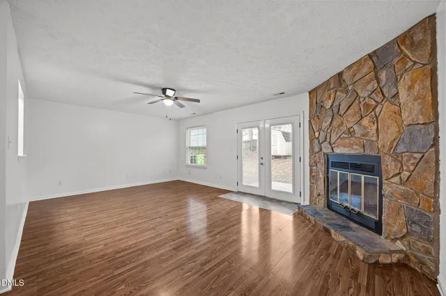 a view of an empty room with a window and wooden floor