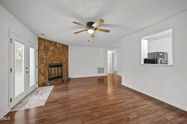 a view of an empty room with a window and a kitchen