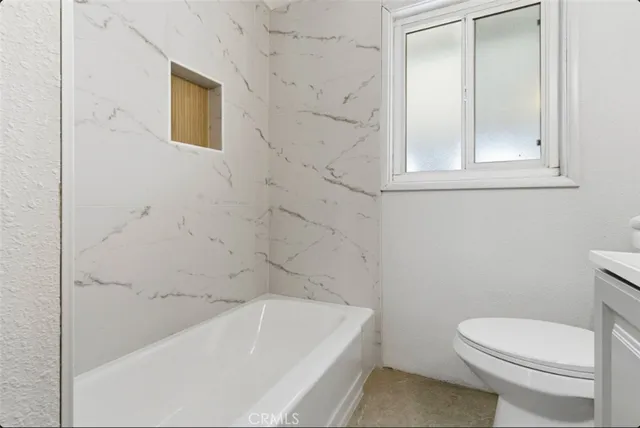 an empty room with wooden floor ceiling fan and windows