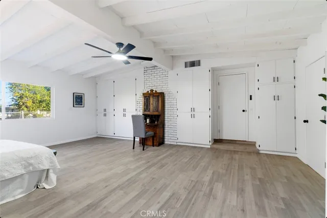 a spacious bedroom with a bed chandelier and a window
