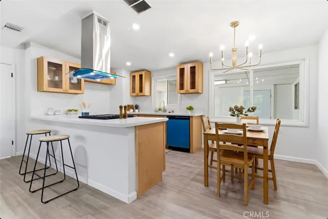 a kitchen with kitchen island stainless steel appliances a dining table chairs sink and cabinets