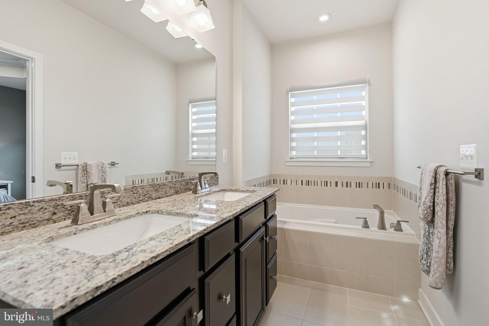 18112 Red Cedar Road Dumfries, VA 22026 - Photo 24 of 69 a bathroom with a granite countertop bathtub a sink and a window