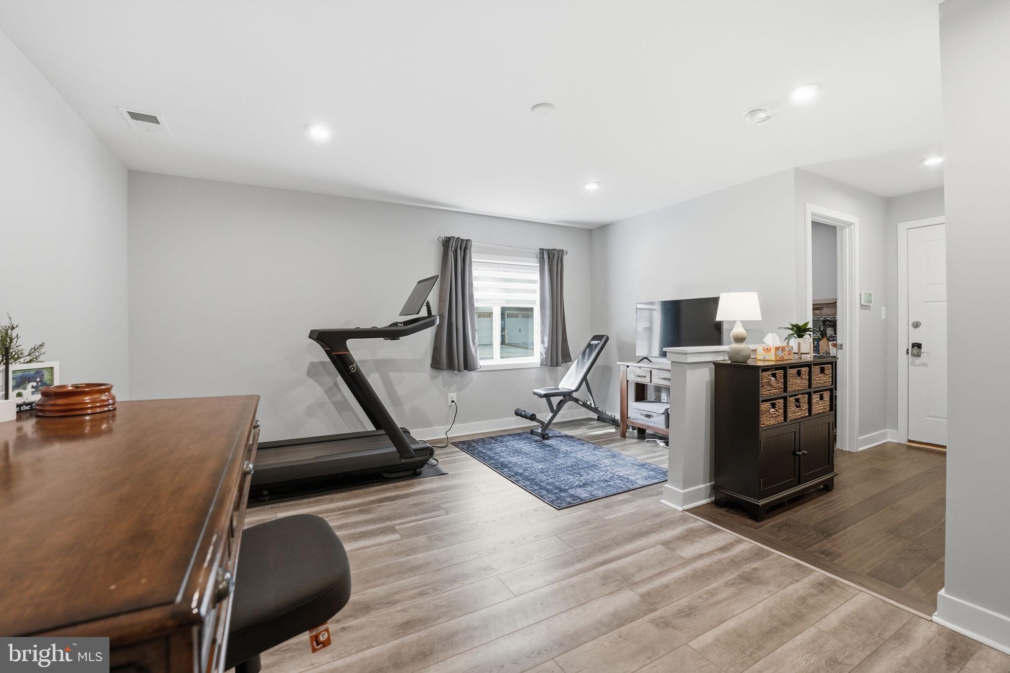 18112 Red Cedar Road Dumfries, VA 22026 - Photo 36 of 69 a living room with furniture a wooden floor and a gym machine