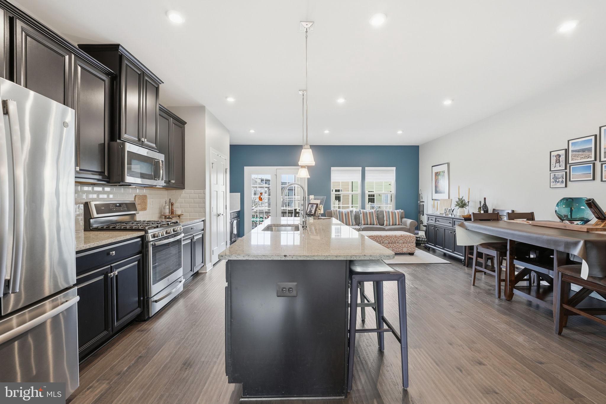 18112 Red Cedar Road Dumfries, VA 22026 - Photo 5 of 69 a kitchen with stainless steel appliances granite countertop a stove refrigerator a dining table and chairs with wooden floor