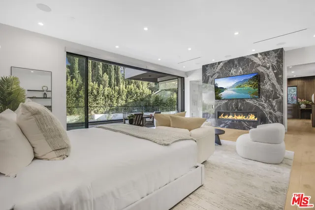 a spacious bedroom with a large bed and a flat tv screen on dresser