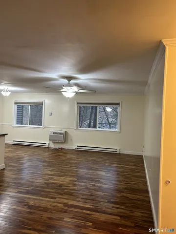 a view of an empty room with window and wooden floor