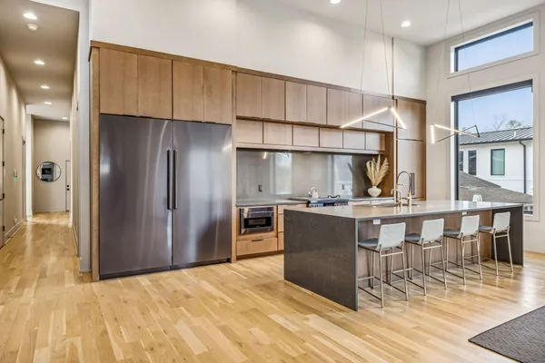 a kitchen with stainless steel appliances kitchen island granite countertop a table chairs in it and wooden floors