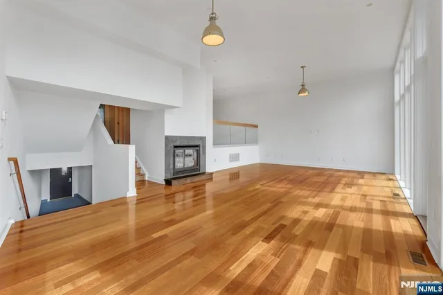 a view of an empty room with window and wooden floor