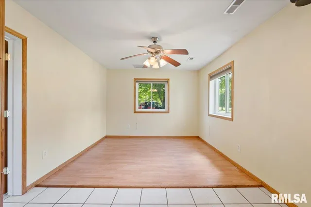 an empty room with windows and ceiling fan
