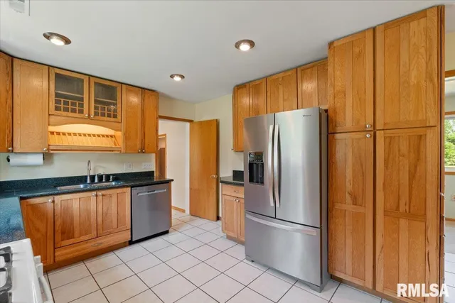 a kitchen with stainless steel appliances granite countertop a refrigerator a sink and cabinets