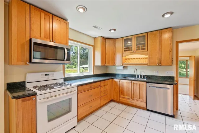 a kitchen with granite countertop cabinets stainless steel appliances a sink and a window