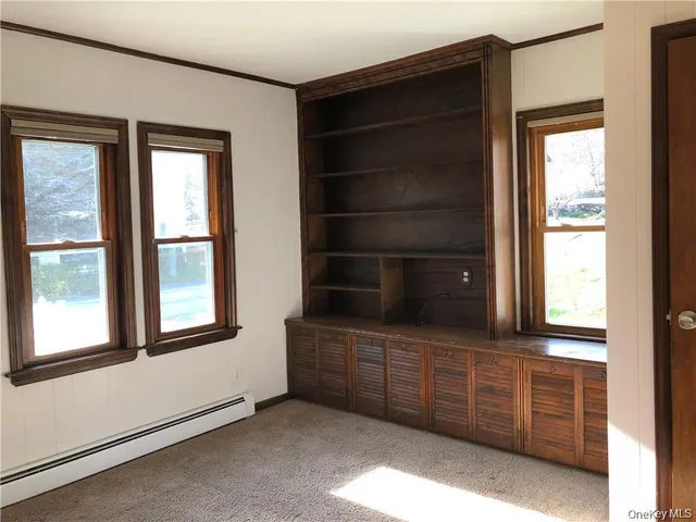an empty room with windows and cabinet